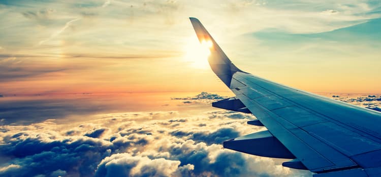 an image of a plane wing over clouds at sunset