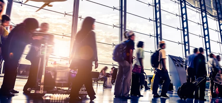 people wait in line at the airport with their suitcases