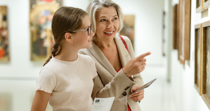A teen and an adult admire paintings in an art museum