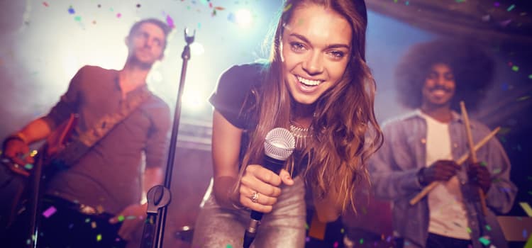 a woman smiles and holds a microphone on a stage