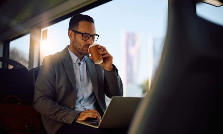 A man works on his laptop while riding in a phoenix charter bus company employee shuttle